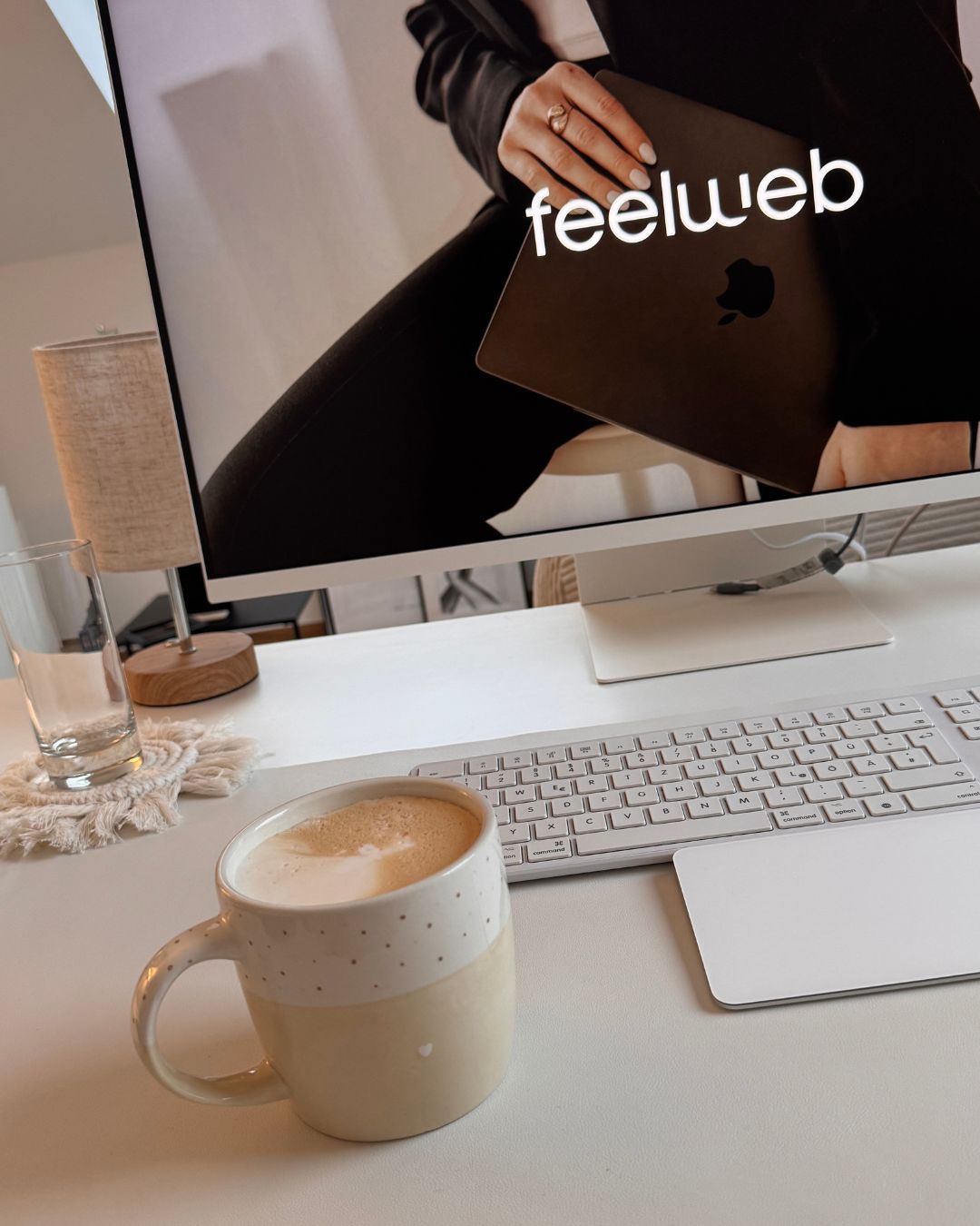 Schreibtisch mit Chai Latte und feelweb auf dem Bildschirm